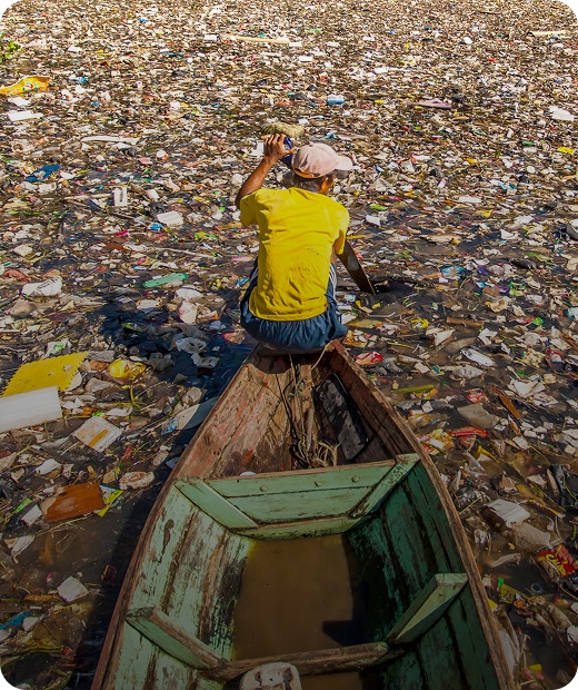 Man on boat padles through river waste