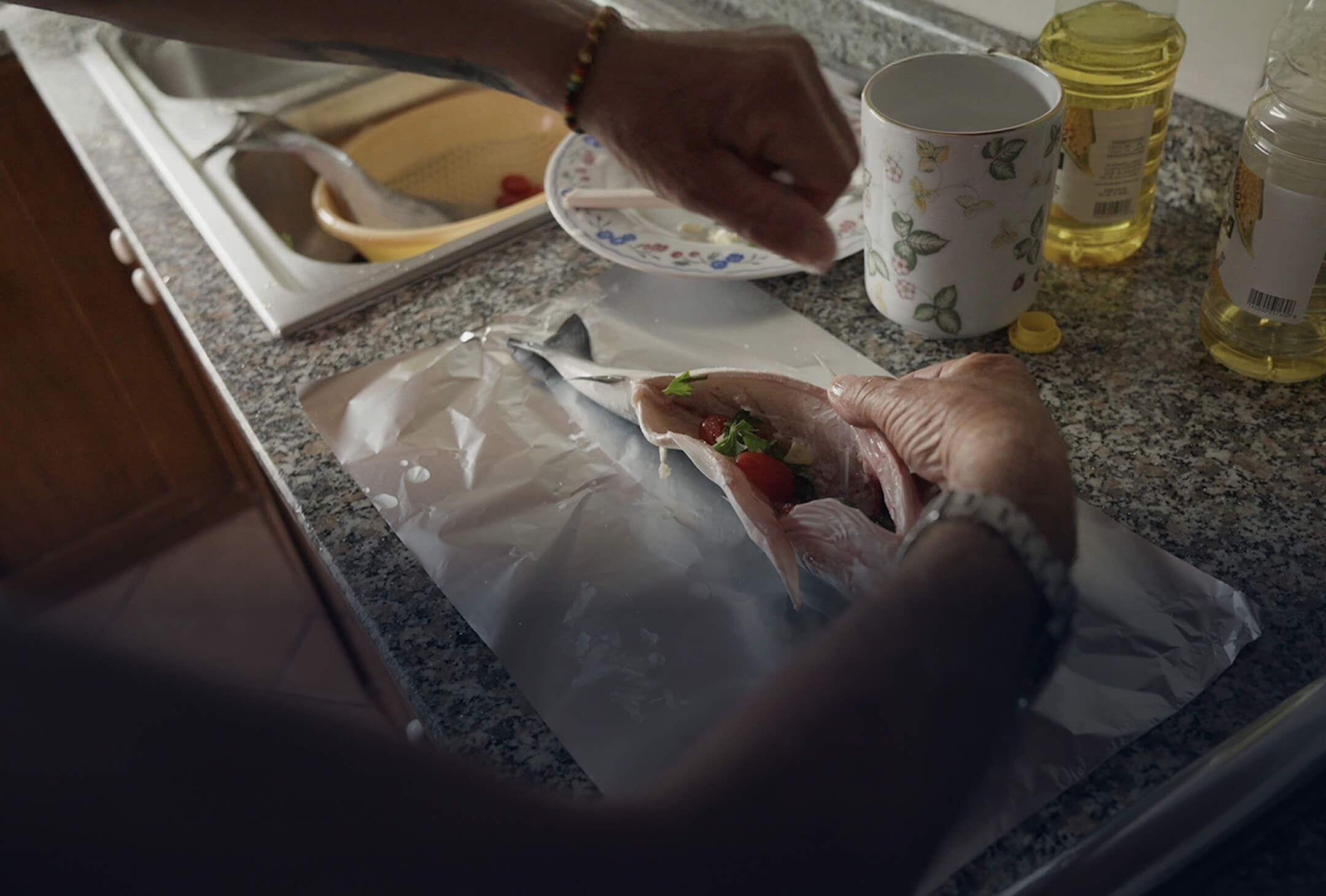 Hands preparing a fish, showing the study of microplastics and plastic pollution in Italy.